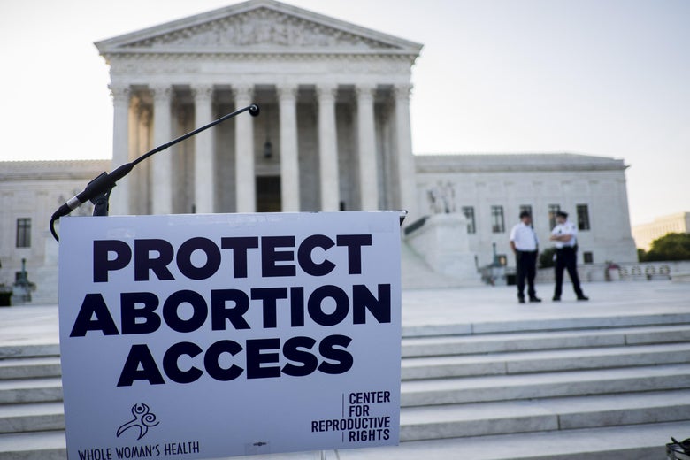 A protest sign reads, "Protect Abortion Access," on a podium in front of the Supreme Court.